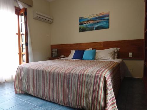 - une chambre avec un grand lit et une couverture rayée dans l'établissement Galápagos ApartHotel, à Ilhabela