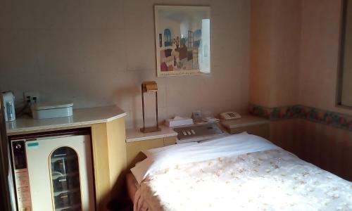 a small room with a bed and a phone at Hotel Ikoma (Love Hotel) in Nagasaki