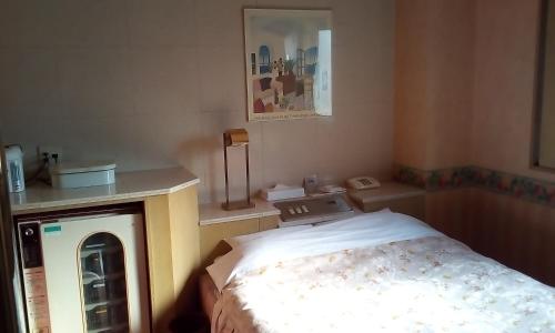 Cette petite chambre comprend un lit et un téléphone. dans l'établissement Hotel Ikoma (Love Hotel), à Nagasaki
