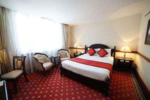 a hotel room with a bed and two chairs at Sammy Dalat Hotel in Da Lat