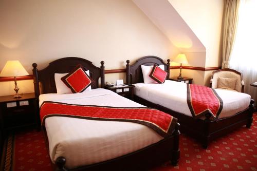 a hotel room with two beds and a chair at Sammy Dalat Hotel in Da Lat
