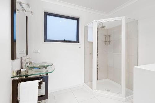 a white bathroom with a glass sink and a shower at Madsen Retreat in Penguin