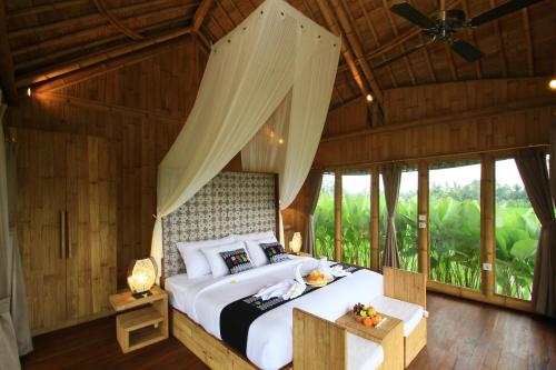 a bedroom with a large bed in a room with windows at Padi Bali Eco Villas in Payangan