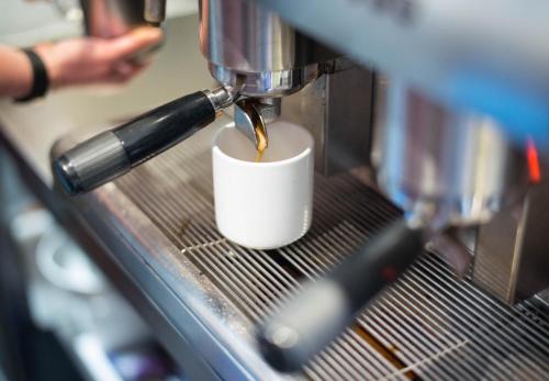 a person is pouring a cup of coffee into a machine at Railway Square YHA in Sydney