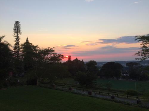 a sunset over a field with a fence and trees at Southey House in Kloof