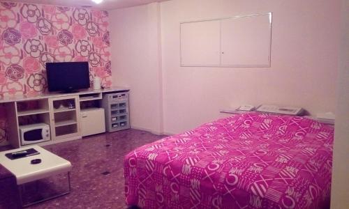 a bedroom with a pink bed and a tv at Hotel Tea Time (Love Hotel) in Nagasaki