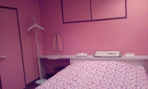 a bedroom with a pink wall with a bed and a desk at Hotel Tea Time (Love Hotel) in Nagasaki