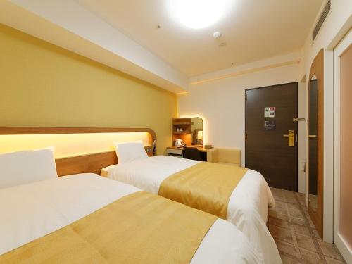 a hotel room with two beds and a door at Hotel Sunroute Sopra Kobe Annesso in Kobe