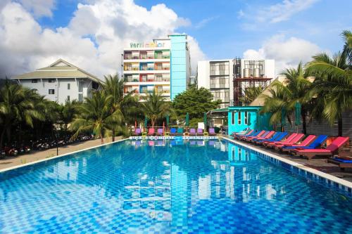 a large swimming pool with chairs and a building at Samui Verticolor in Chaweng