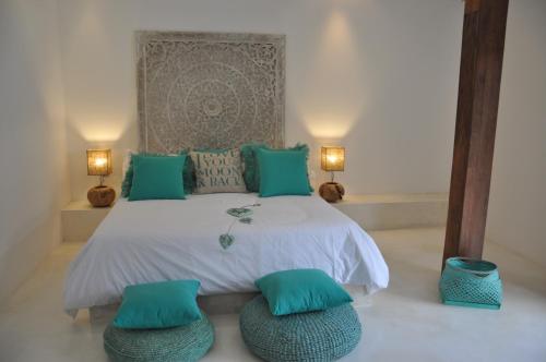 een slaapkamer met een bed met blauwe kussens en twee lampen bij Villa Enjoy in Canggu