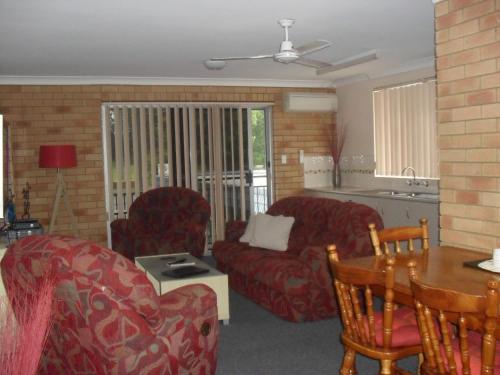 a living room with red furniture and a kitchen at Beachlander Self-Contained Holiday Apartments in Coffs Harbour