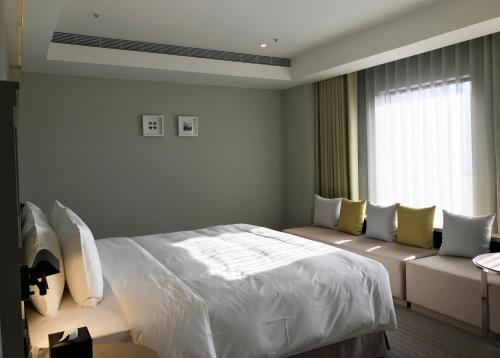a bedroom with a bed and a couch and a window at Greet Inn in Kaohsiung