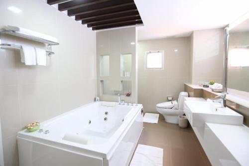 a white bathroom with two sinks and a toilet at J Town Serviced Apartments & Hotel in Si Racha