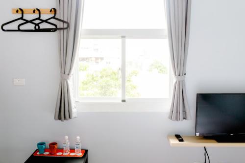 Una sala de estar con televisión y una ventana. en FUNDI Hotel, en Tainan