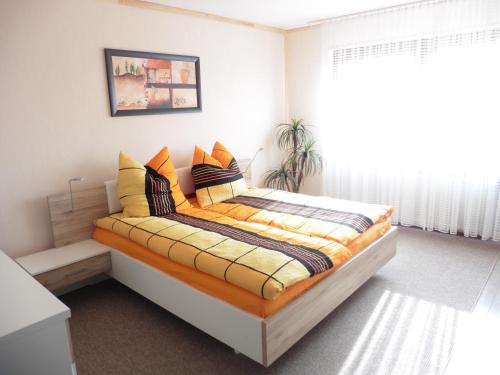 Schlafzimmer mit einem Bett mit orangefarbener und gelber Bettwäsche in der Unterkunft Ferienwohnung ,,Wingertsberg" in Ebrach