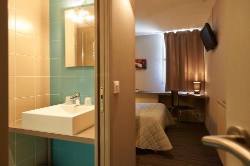 ein Bad mit einem Waschbecken und ein Bett in einem Zimmer in der Unterkunft Cit'Hotel Les Alizés in Limoges
