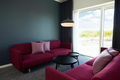 a living room with a red couch and a table at Best Western Plus Hotel Fredericia in Fredericia