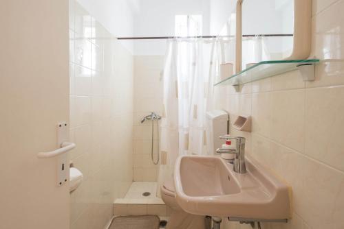 a white bathroom with a sink and a shower at Erato Apartments in Petalidhion