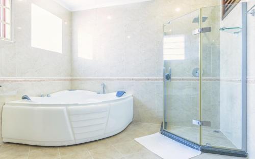a bathroom with a tub and a glass shower at HAMPTONS Apartments in Phnom Penh