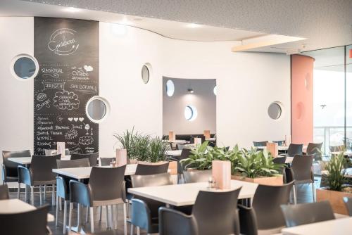 a dining room with tables and chairs and a chalkboard at Hotel und Therme NOVA in Köflach