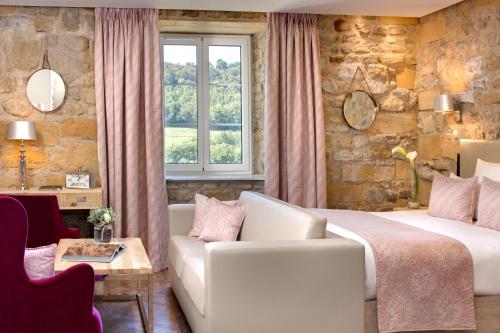 a bedroom with a bed and a couch and a window at Domaine de la Klauss & Spa, Restaurant Gastronomique Le K in Montenach