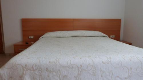 a bedroom with a white bed with a wooden headboard at Hostal Restaurante La Masía in Villareal