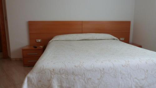 a bedroom with a bed and a wooden headboard at Hostal Restaurante La Masía in Villareal