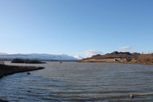 a river with snow covered mountains in the background at Ormurinn Guesthouse in Egilsstadir