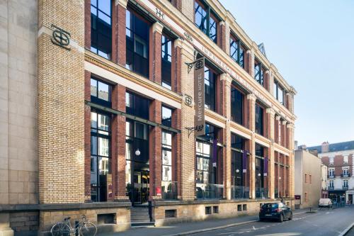 a large brick building with a car parked in front of it at Mercure Rennes Centre Parlement in Rennes