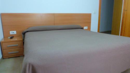 a bedroom with a bed and a wooden headboard at Hostal Restaurante La Masía in Villareal