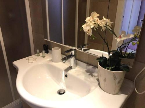 a bathroom sink with a vase with flowers on it at Villa Tivoli in Guidonia