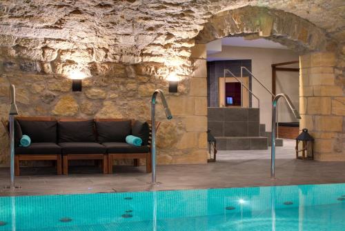 a living room with a couch next to a swimming pool at Domaine de la Klauss & Spa, Restaurant Gastronomique Le K in Montenach
