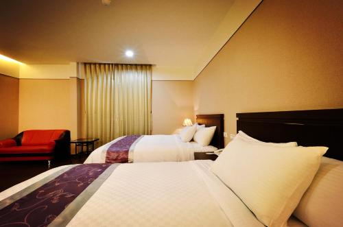 a hotel room with two beds and a red chair at King Town Hotel in Luodong