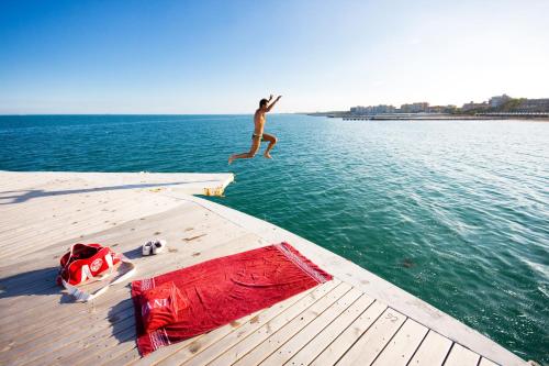 a man jumping off a dock into the water at Hotel Villa Pannonia in Venice-Lido