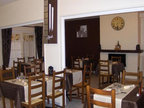 un restaurante con mesas y sillas y un reloj en la pared en La Tour de Crecy, en Crécy-sur-Serre