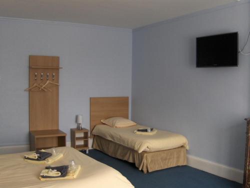 a hotel room with two beds and a flat screen tv at La Tour de Crecy in Crécy-sur-Serre