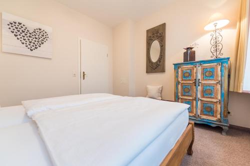 a bedroom with a white bed and a blue dresser at Hotel Villa Waldfrieden in Ostseebad Sellin