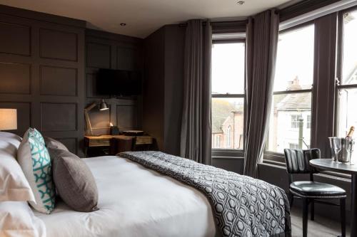 una camera d'albergo con letto, scrivania e finestre di The Driftwood Bexhill a Bexhill
