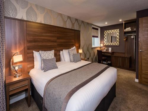 a hotel room with a large bed and a desk at The Melbreak Hotel in Great Clifton