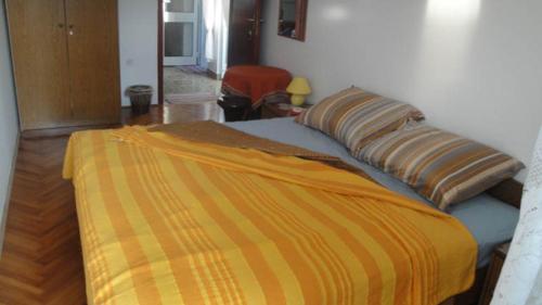 a bed with an orange and yellow blanket on it at Villa Bencun in Medulin