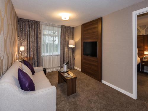 a living room with a white couch and a tv at The Melbreak Hotel in Great Clifton