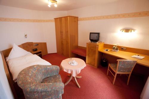 a hotel room with a bed and a desk and a chair at Landhotel Teuteberg in Bad Arolsen