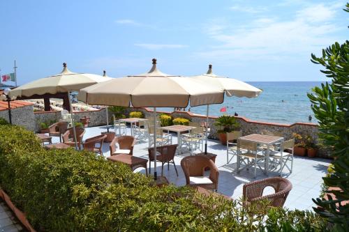 a patio with tables and chairs with the ocean in the background at Hotel La Nave in Sperlonga