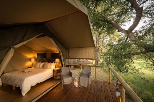 a bedroom in a tent with a bed on a deck at Rukiya Safari Camp in Hoedspruit