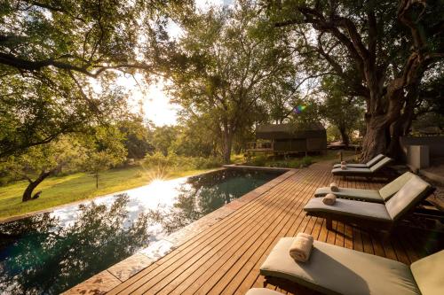 a wooden deck with chairs and a swimming pool at Rukiya Safari Camp in Hoedspruit