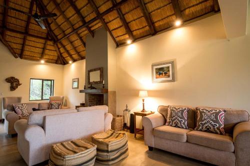 a living room with two couches and a fireplace at Rukiya Safari Camp in Hoedspruit