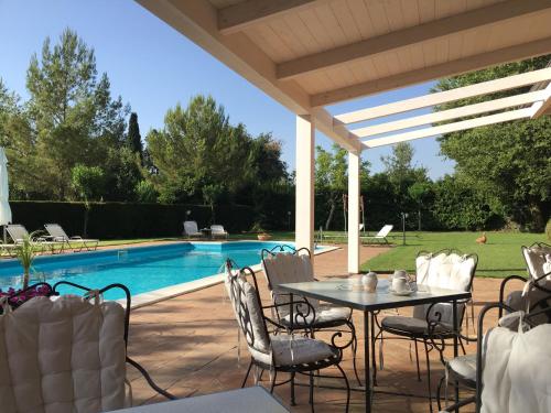 Bed and Breakfast Il Glicine في بيديمونتي إتنيو: فناء مع طاولة وكراسي بجوار حمام السباحة