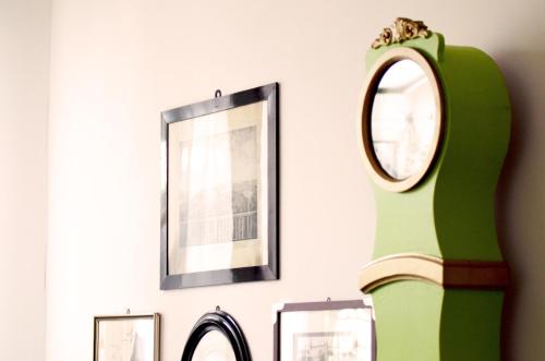 a mirror and a green vase on a wall with pictures at Georg Rass Gästehaus in Norderney