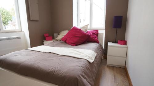 Un dormitorio con una cama con almohadas rojas. en L'appartement Richard, en Beaune