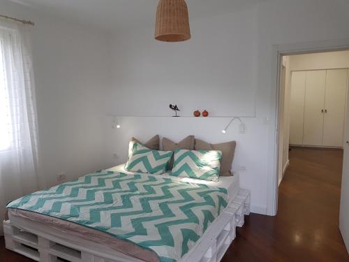 a bedroom with a bed with a green and white comforter at Bright Central Apartman in Tivat
